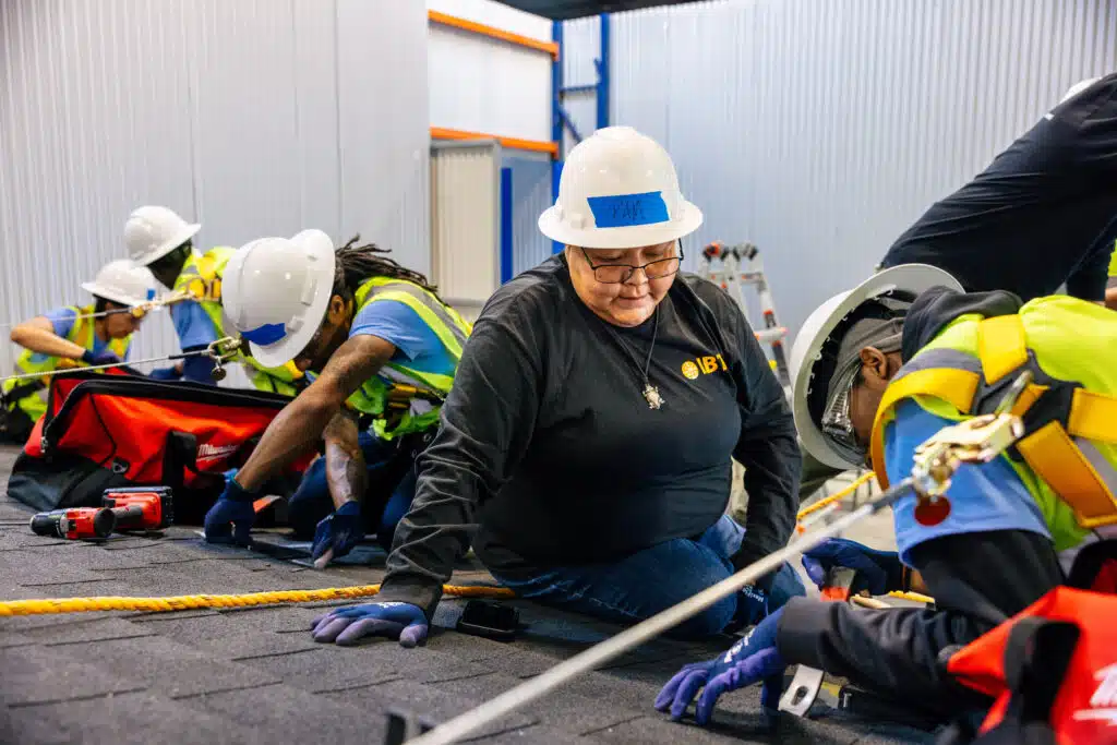 Construction workers in safety gear practicing rope handling during IBT training in warehouse