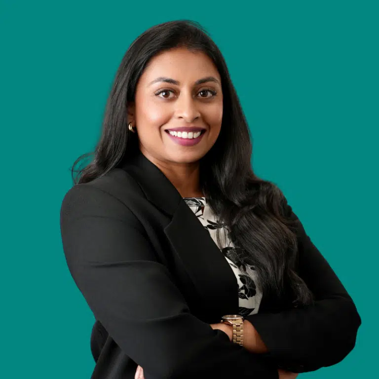 A woman in a black blazer, against a deep teal background.